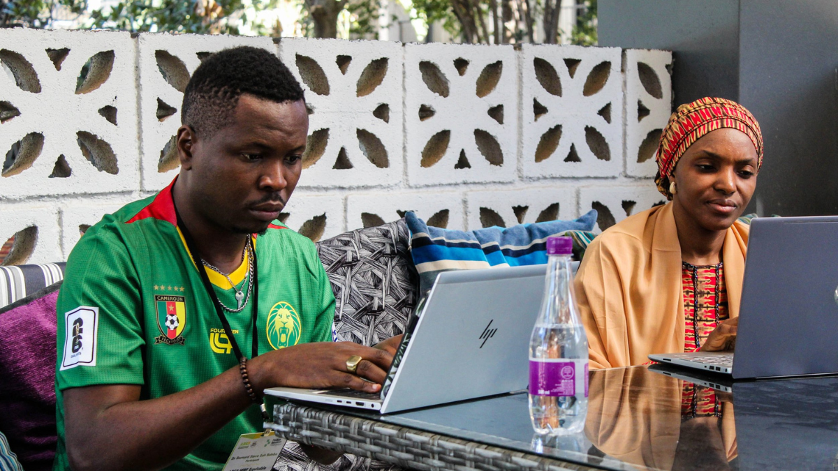 Two of our funded Impact of Climate Change on Health researchers, Dr Bernard Steve Soh Baleba (left) and Dr Seniyat Afegbua (right) at our Equitable Partnerships Training in Botswana. Both are working outside on laptops.