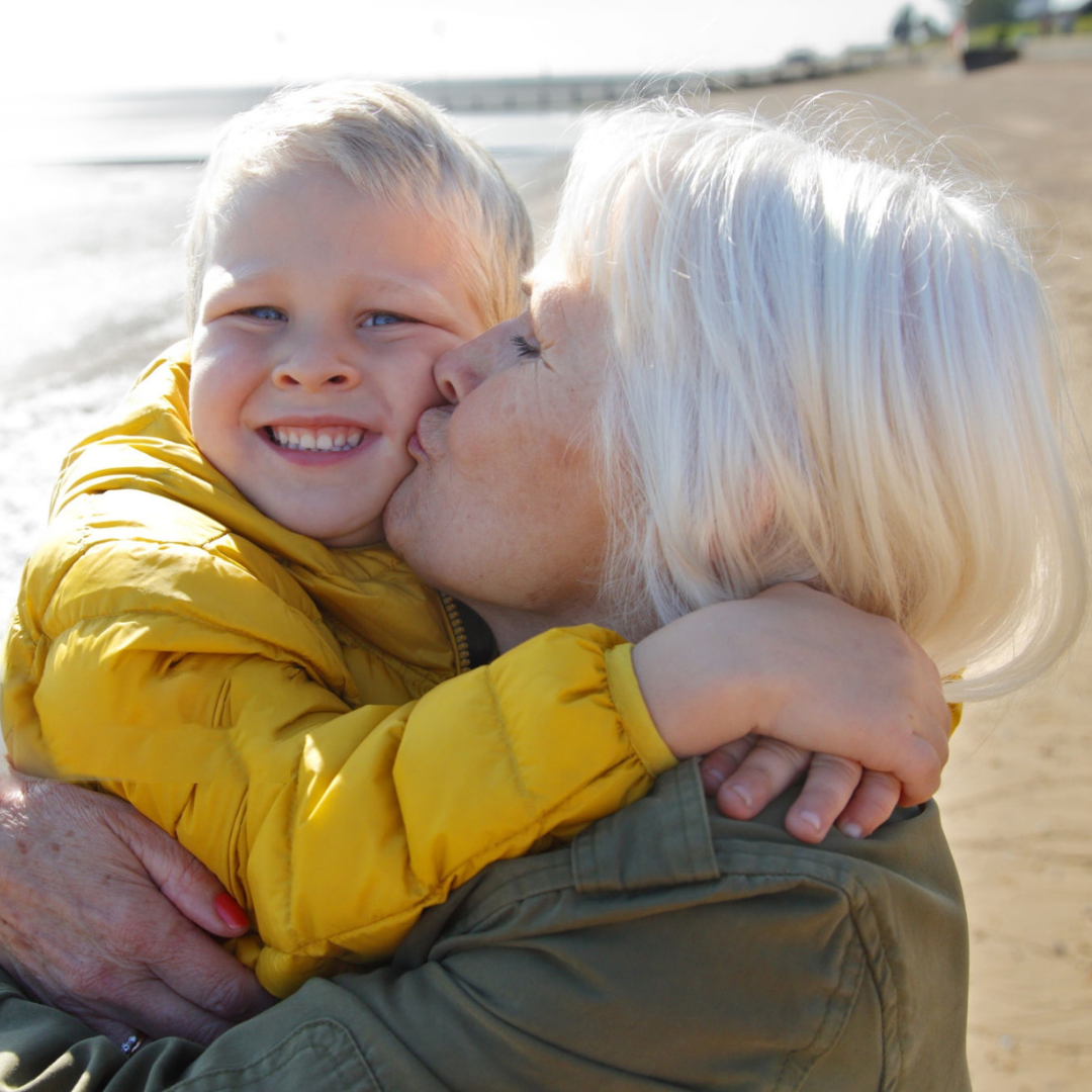 An older woman carrying a young boy at the seaside